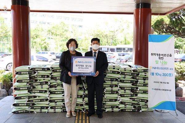 농협생명 사업1부문 신상종 부사장(사진 오른쪽)과 은평노인종합복지관 김승자 관장이 중복을 맞아 쌀 나눔을 기념해 사진을 촬영하고 있다. [사진=농협생명 제공]